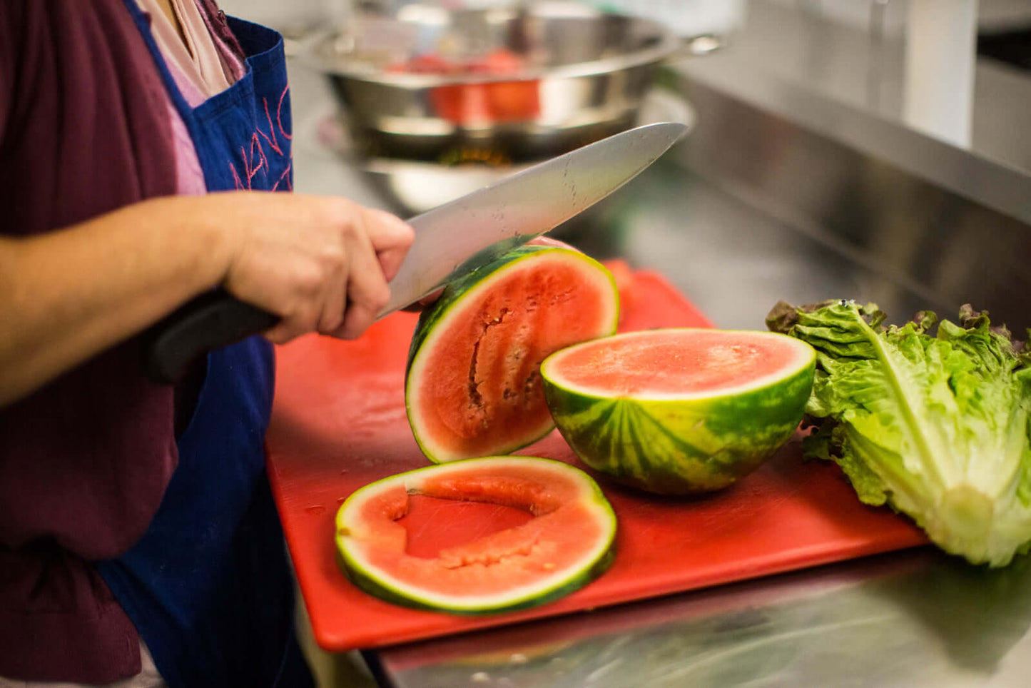Nancia's Antojitos - woman cutting watermelon in community kitchen