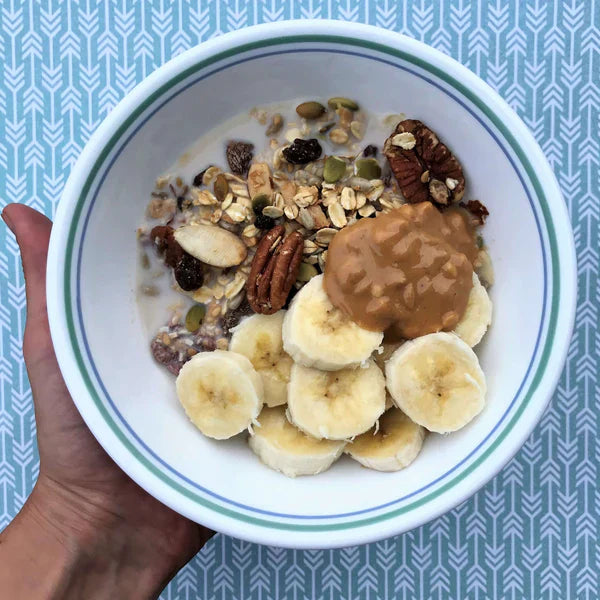 Michele's Toasted Muesli bowl topped with sliced bananas, and a dollop of peanut butter.