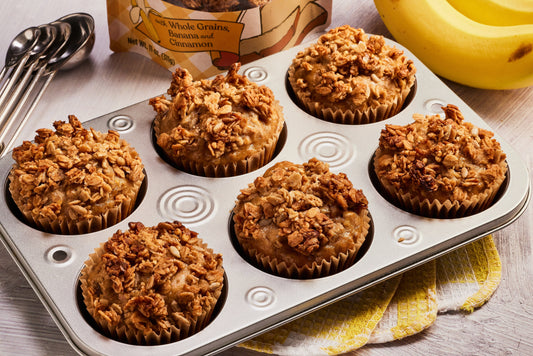 A muffin tin of freshly baked Double Banana Bread Muffins, topped with granola