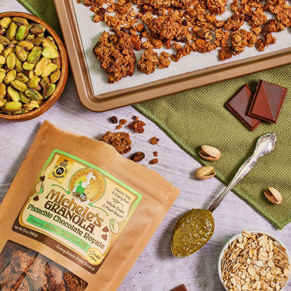 Michele's Pistachio Chocolate Royale Granola 12oz bag with sheet pan of granola and bowls of ingredients including pistachios, oats, and chocolate